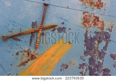 Two rusty old nail lying on a metallic blue background color.
