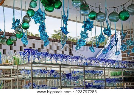 CABO SAN LUCAS, MEXICO - April 8, 2014: Stands with colorful mexican wine glasses, vases and glass decorations at Los Cabos glass factory store