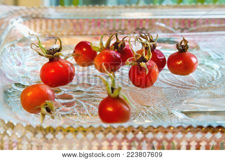 Rose hips from Rosa rugosa on a glass plate. Close up.