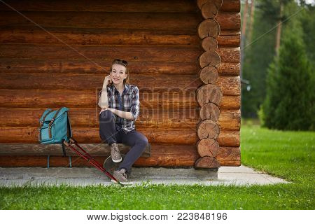 young beautiful woman with nordic walk pols resting near country house. outdoor summer shot. copy space.