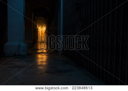 Empty dark street at night with light of latern shining through arches, Georgetown, Penang, Malaysia