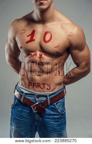 Shirtless muscular young guy with red text on his pody. Isolated on grey background.