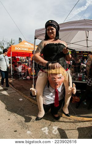 ATLANTA, GA - OCTOBER 2017:  A woman wears a costume in which she appears to be a dominatrix riding the shoulders of President Donald Trump, at the Little Five Points Halloween parade in Atlanta, GA on October 21, 2017.