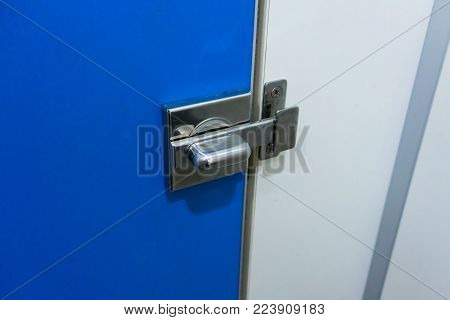 Metal lock latch for lock the toilet blue door in the public toilet.