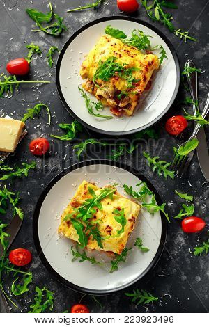 Homemade lasagna with minced beef bolognese and bechamel sauce topped wild arugula, parmesan cheese.