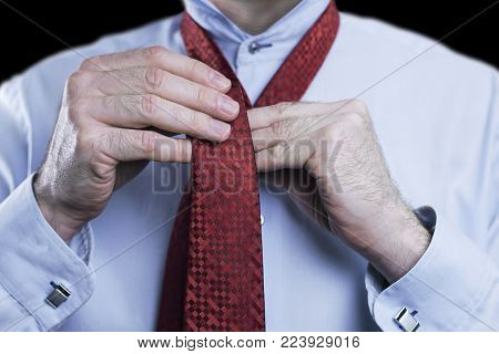 Close up of a businessman tying knot on red tie, getting ready