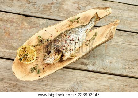 Cooked fish on a wooden plate, top view. Stuffed cooked fish on a wooden plate.