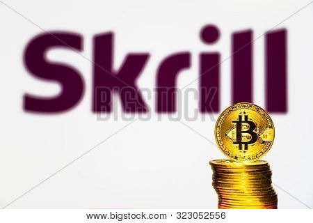 Gold Bitcoin Coins With The Skrill Logo On Background Screen. A New Type Of Business Finance Concept