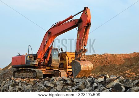 Heavy Excavator Working At Gravel Quarry Unloads Old Concrete Stones For Crushing And Recycling To G