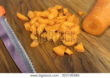 Close Up Of Chopped Carrots With Knife On Wood Table.