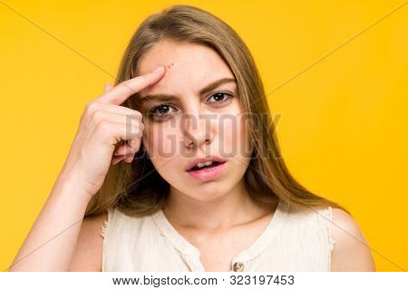 Portrait Of Sad Teen Gerl Touching Her Face And Looking For Acne On Yellow Background