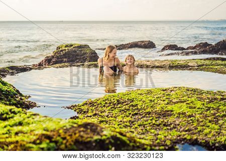 Mother And Son Tourists On Pantai Tegal Wangi Beach Sitting In A Bath Of Sea Water, Bali Island, Ind