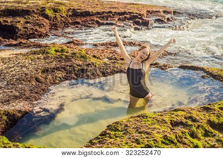 Young Woman Tourist On Pantai Tegal Wangi Beach Sitting In A Bath Of Sea Water, Bali Island, Indones