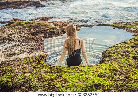 Young Woman Tourist On Pantai Tegal Wangi Beach Sitting In A Bath Of Sea Water, Bali Island, Indones