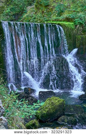 Waterfall At Source Du Doubs Mouthe Franche Comté France With Green Plants On A Sunny Day