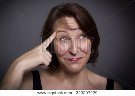 Woman Grimaces In Front Of Camera On Gray Background