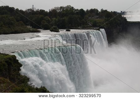 Close up of Niagara falls viewed from usa in the day with the bright sun, with a lot of mist