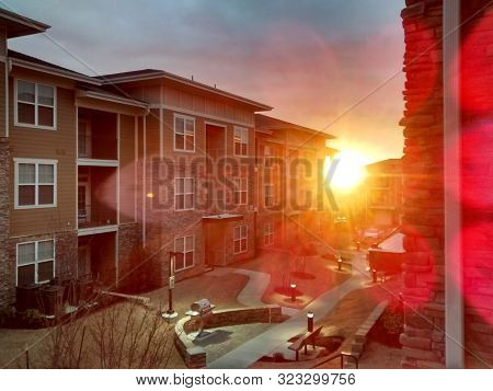 Bright sun beaming through apartment neighborhood with a bbq grill visible by the path