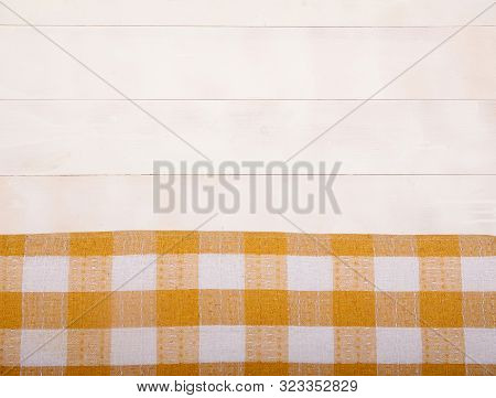 Linen Yellow Tablecloth Lies On A White Wooden Background. Horizontally. View From Above. Copy Spaes
