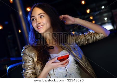 Retrato de jovem mulher atraente no clube de noite com uma bebida