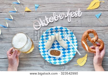 Oktoberfest, Traditional Festival Food: White Sausages, Hands Holding Pretzel And Beer. Flat Lay On 