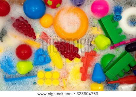Different Toys In Soapy Foam. Clean Toys Protect Children From Viruses And Bacteria. Background From