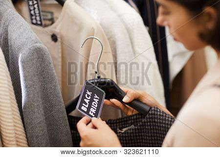 Closeup Of Unrecognizable Young Woman Holding Autumn Coat With Black Friday Tag While Browsing Cloth