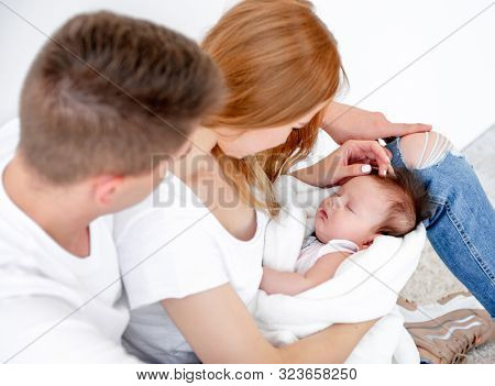 Father, mother and sleeping baby girl at home