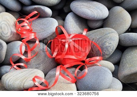 Red Heart On A Background Of Gray Stones. Scarlet Ribbon And Bow