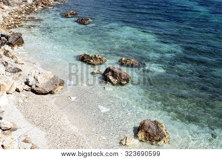 Greece, The Island Of Paros. A View From The Cliffs At The Resort Of Piso Livadi. A Pebbly Beach Wit