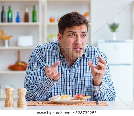 Young husband eating tasteless food at home for lunch