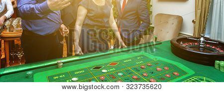 Group Of People Behind Roulette Gambling Table In Luxury Casino. Friends Playing Poker At Roulette T