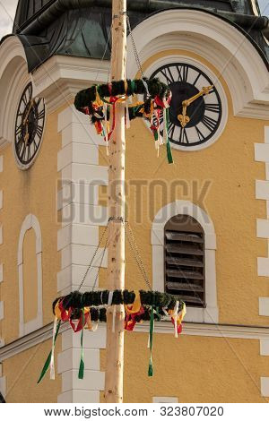 View Of A Church Tower In The Background With A Maypole In The Foreground. The Maypole Is One Of The