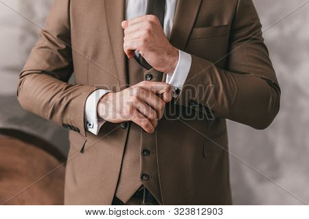 Elegant Young Fashion Man Looking At His Cufflinks While Fixing Them. Photo Of Male Hands. Handsome 