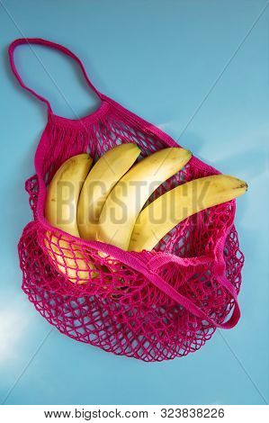Organic Banana In Mesh String Bag On Pastel Blue Paper Background. Flat Lay, Top View. Zero Waste, P
