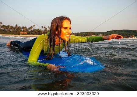 Sports Beautiful Woman In A Diving Suit Lying On A Surfboard Waiting For A Big Wave .surf Girl In A 