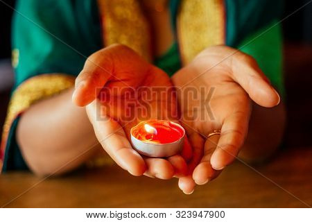 Woman Lighting Diyas With Nuth Nath Nose Piercing And The Golden Teak With Traditionak Fashion Sari