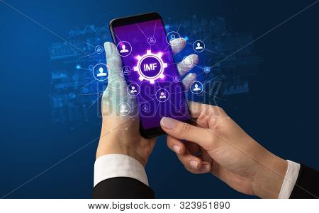 Female hand holding smartphone with IMF abbreviation, modern technology concept