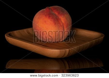 One Whole Fresh Fuzzy Peach On Wooden Square Plate Isolated On Black Glass