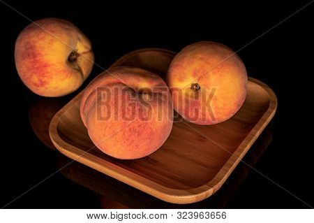 Group Of Three Whole Fresh Fuzzy Peach On Wooden Square Plate Isolated On Black Glass