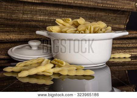 Lot Of Whole Uncooked Pasta Cavatelli In Ceramic Stewpan With Brown Textil Cloth Isolated On Black G