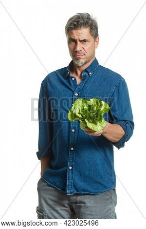 Casual older white man man holding green salad - healthy eating. Disappointed and misgiving.