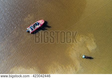 Men's Company On A Fishing Trip. Two Are Fishing On A Spinning Boat, One Is Standing Knee-deep In Th