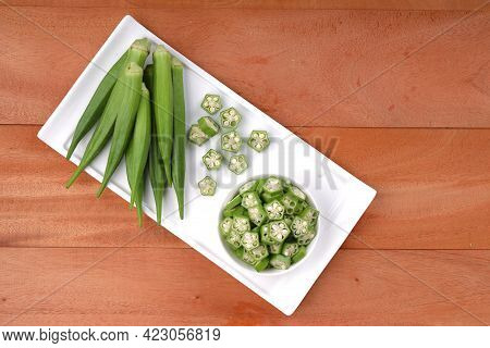 Okra Or Lady's Finger Or Bhindi Fresh Green Vegetable Arranged  On A White Tableware With A  Bowl Fu