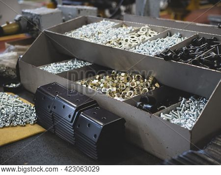 Different Types Of Fasteners On The Worker's Table. Work Place At The Assembling Shop. Bolts And Nut