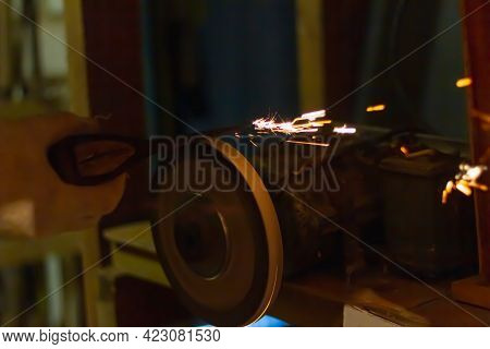 Sharpen The Axe Tool On The Rotating Grinding Wheel, Sparks Fly From The Metal.
