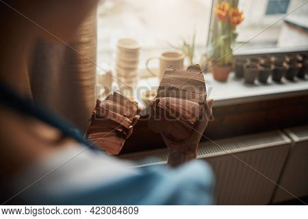 Unrecognized Female Ceramicist In Apron Looking To The Earthenware Product In Art Workshop