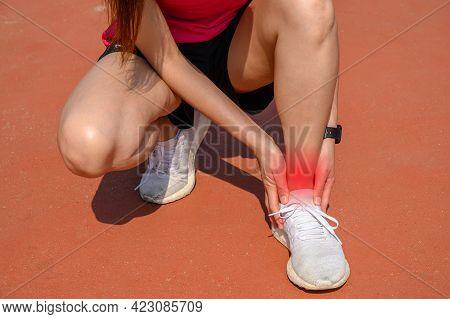 Cropped Shot Of Woman Runner Kneel Down, Suffering From Ankle Pain. Ankle Pain May Be Caused By An I
