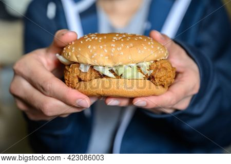Close Up Of Someone Holding Fresh Delicious Crispy Chicken Burger Before Eating. A Hamburger Is A Sa