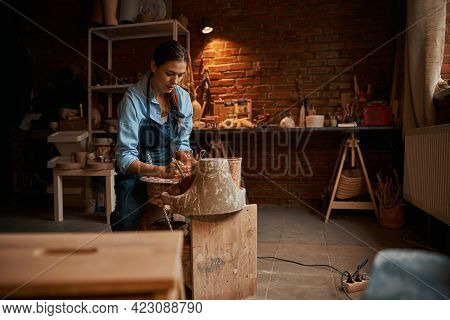 Happy Attractive Focused Ceramicist Working With Earthenware Tableware On Pottery Wheel In Workshop